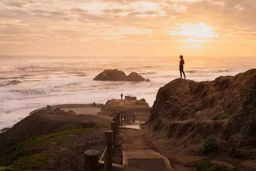 Duas pessoas estão em rochas 和 vista para o oceano em Sutro Baths, em 贝博体彩app.